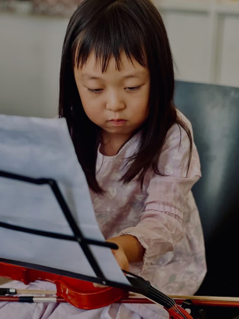 Young student reading sheet music while holding a violin